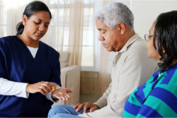 Caregiver is giving medicines to the old man
